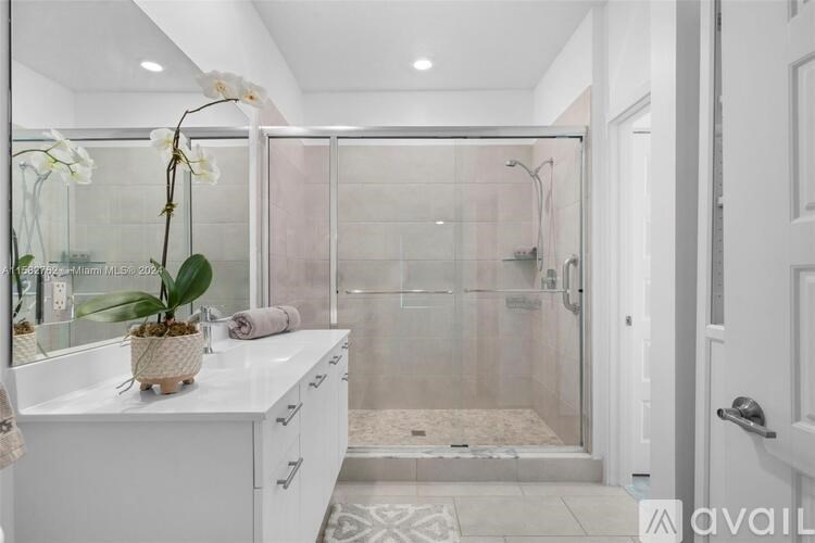 A bathroom with a glass shower enclosure and a white vanity.