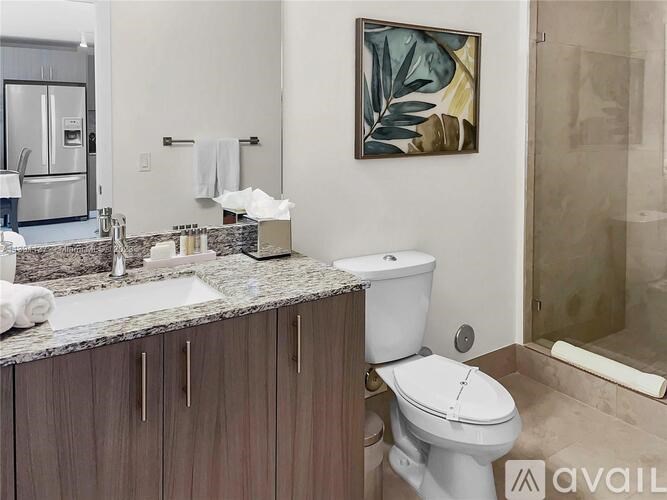 A bathroom with a toilet, sink, and a painting on the wall.