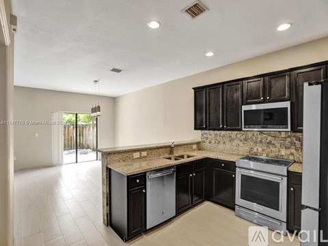 A kitchen with black cabinets and a granite countertop.