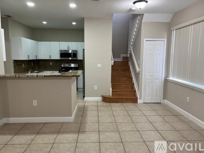 A kitchen with a staircase leading to the upper floor.