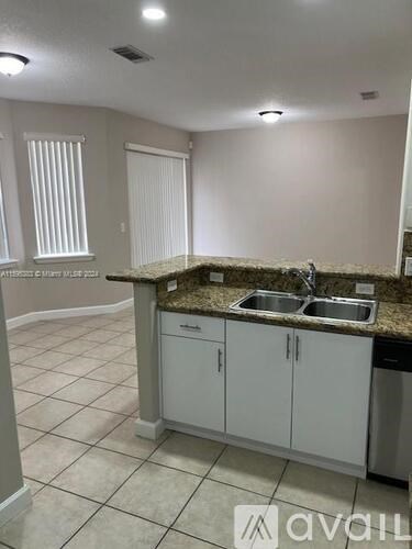 A kitchen with granite countertops and white cabinets.