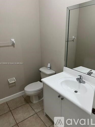 A white bathroom with a toilet, sink and mirror.
