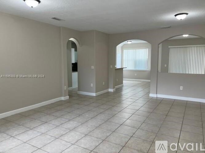 A spacious room with tiled flooring and arched doorways.