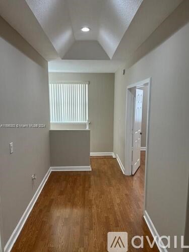 A hallway with wood floors and white walls.
