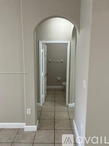A hallway with a white door and tiled floor.