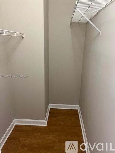 A hallway with a wooden floor and white walls.