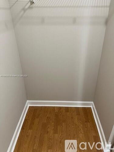 A room with wooden flooring and white walls.