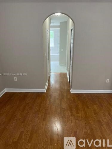 A hallway with wooden floors and a white door.