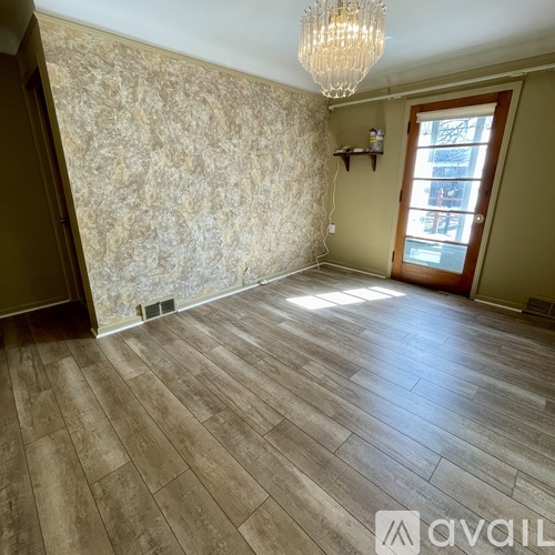 A room with wooden flooring and a chandelier.