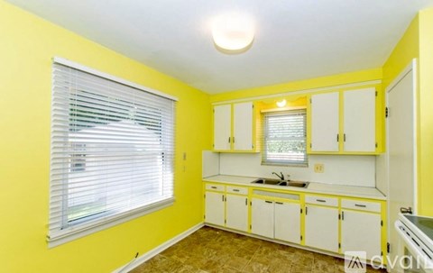 A kitchen with yellow walls and white cabinets.