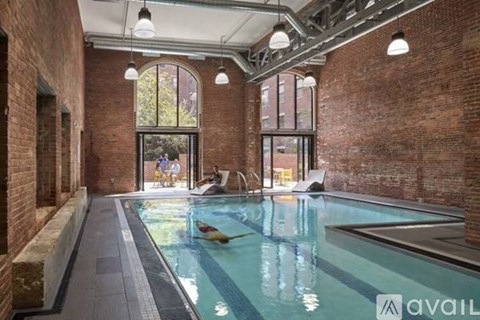 A large indoor swimming pool with a glass wall and brick walls.