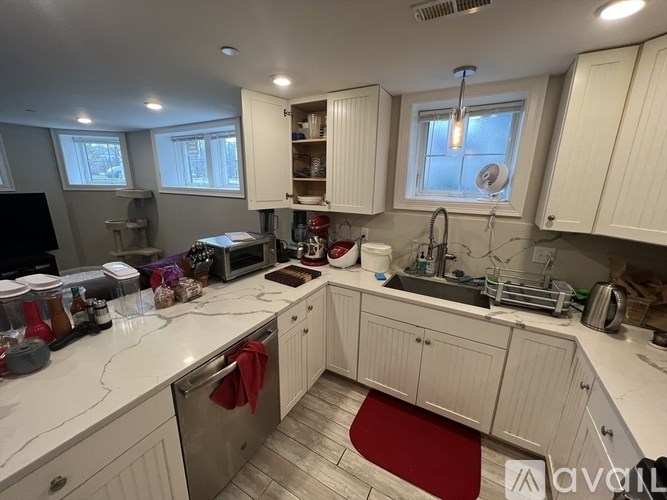 A kitchen with white cabinets and a red rug on the floor.