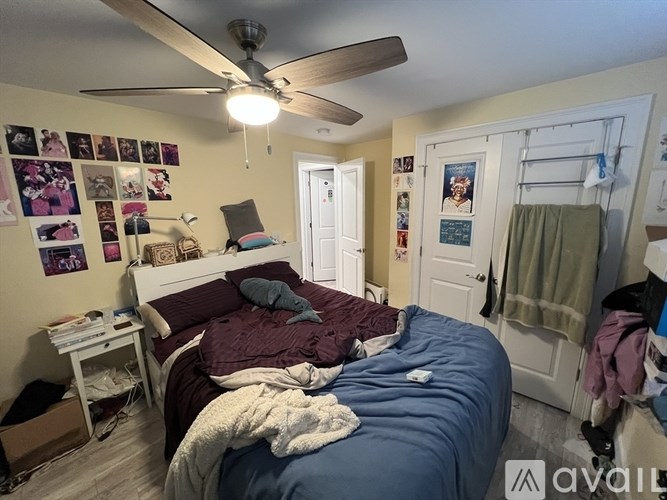 A bedroom with a bed, a ceiling fan, and pictures on the wall.