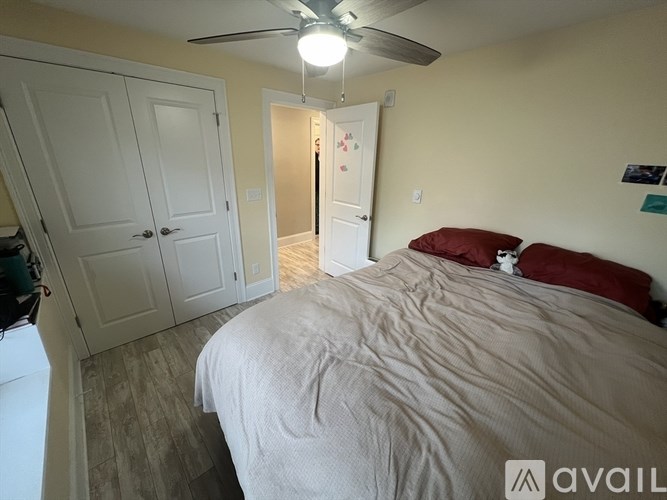 A bedroom with a bed, a ceiling fan, and a door leading to another room.