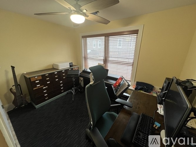 A room with a desk, chairs, and a guitar.