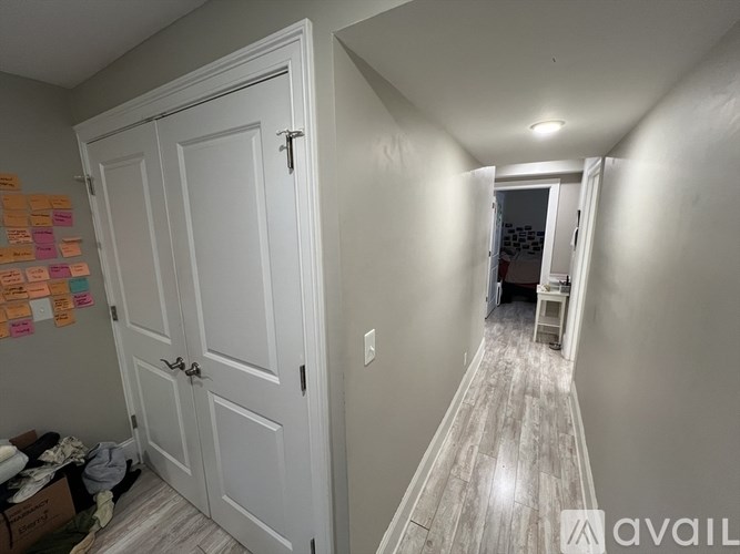 A hallway with a white door and a white cabinet with sticky notes on the wall.