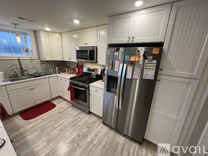 A kitchen with white cabinets and a refrigerator with magnets on it.