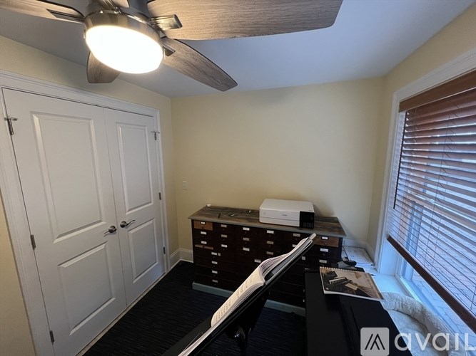 A room with a ceiling fan and a dresser with a printer on top.