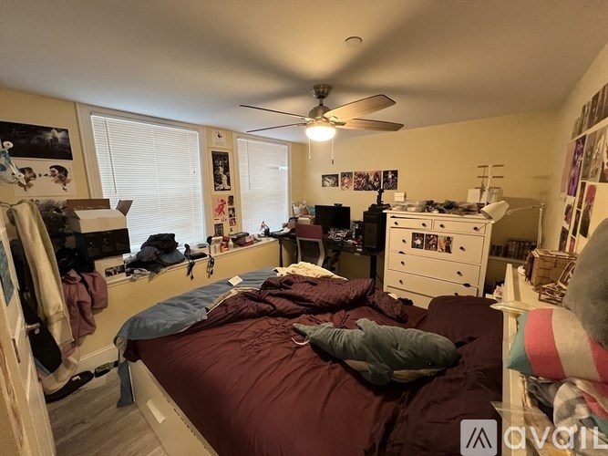 A bedroom with a bed, dresser, and a ceiling fan.