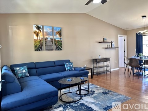 A living room with a blue sofa and a painting of a beach scene on the wall.