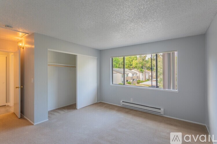 A room with a window showing a view of a street and houses outside.