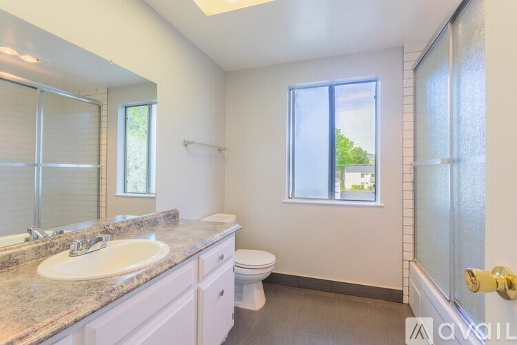 A bathroom with a sink, toilet, and window.