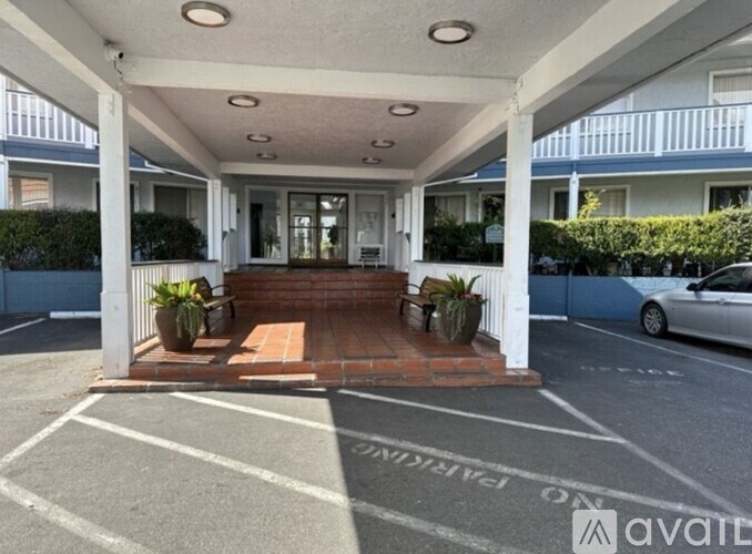 A car is parked in a parking lot with a building entrance in the background.