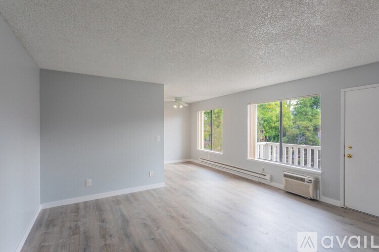A spacious room with wooden floors and a window overlooking a balcony.