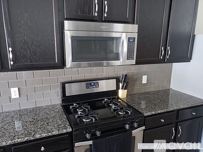 A kitchen with black cabinets and a granite countertop.