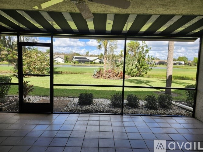 A patio with a view of a green lawn and trees.