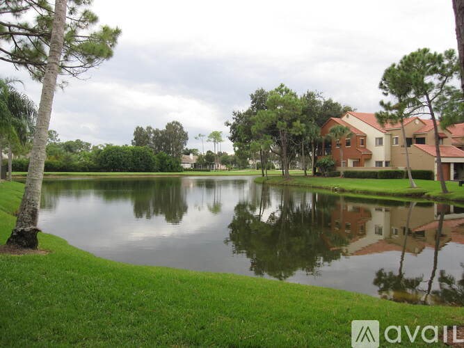A lake in front of a house with trees around.