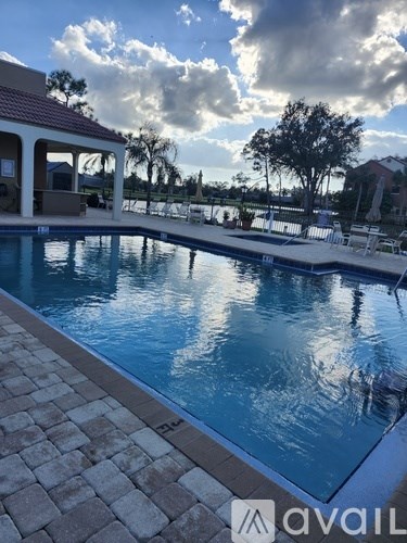 A pool with a pavilion and chairs around it.