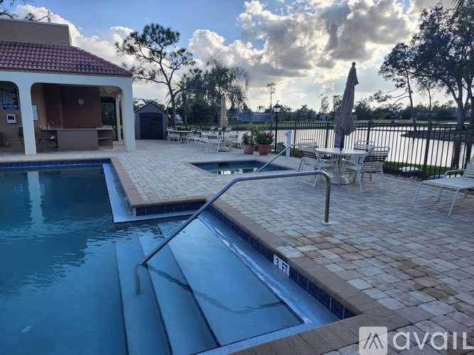 A pool with a slide and a patio area with chairs and an umbrella.