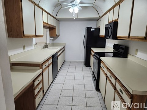 A kitchen with black appliances and white countertops.
