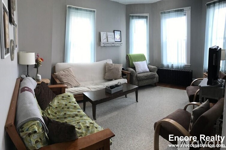 A living room with a white couch, a green chair, and a wooden coffee table.