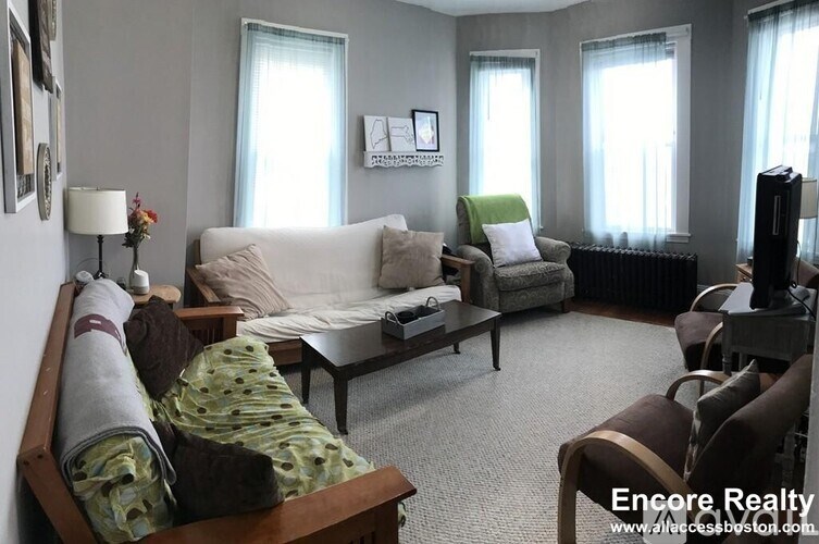 A living room with a white couch, a green chair, and a wooden coffee table.