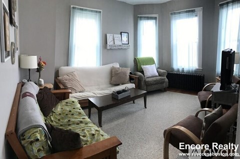 A living room with a white couch, a green chair, and a wooden coffee table.