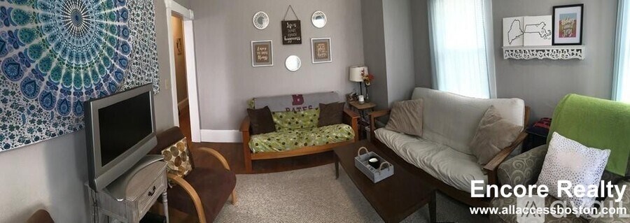 A living room with a couch, a television, and a bed.