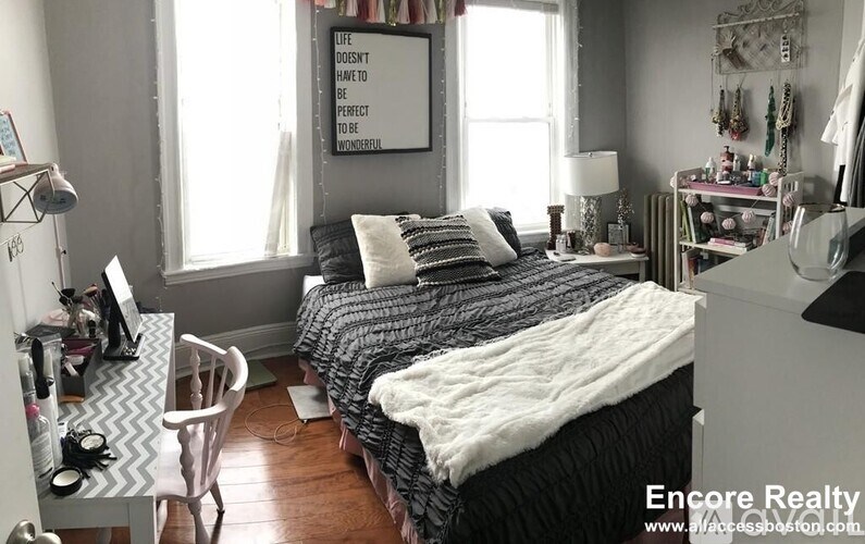 A bedroom with a bed, desk, chair, and a poster on the wall.
