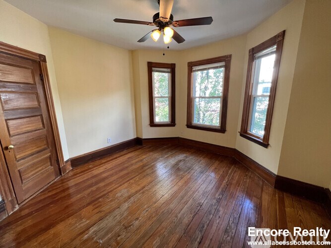 A room with wooden floors and a ceiling fan.