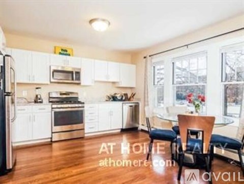 A kitchen with white cabinets and a refrigerator.