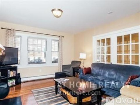 A living room with a black couch and a television.