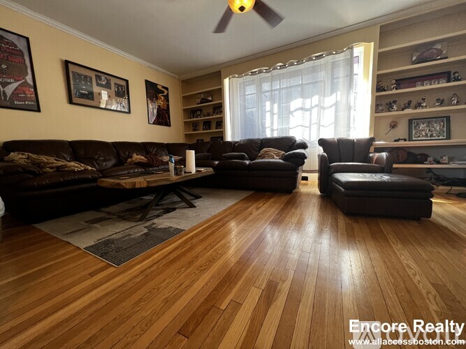 A living room with a brown leather couch and a wooden floor.