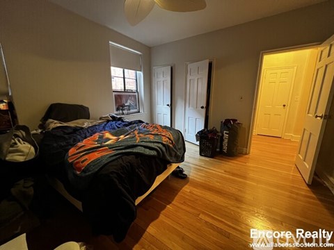 A bedroom with a bed covered in a blue and orange blanket.
