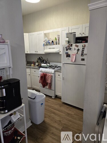 A kitchen with white cabinets and a refrigerator covered in magnets.