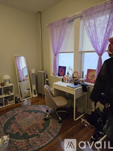 A room with a desk, chair, and a rug with a cat on it.