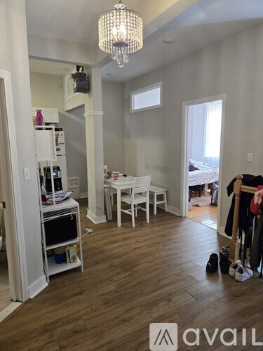 A room with a chandelier, a dining table, and a kitchenette.