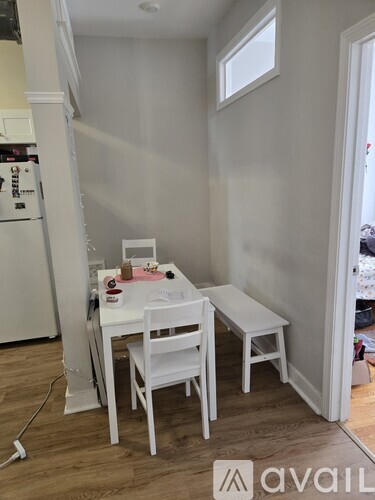 A white table and chairs are set up in a room with a white refrigerator.