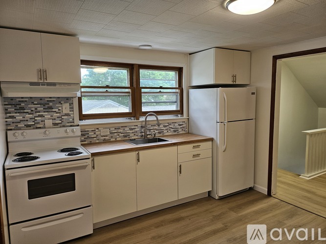 A kitchen with white appliances and wooden floors.