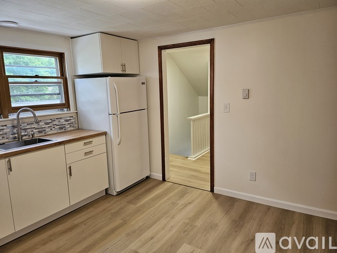 A kitchen with white appliances and wooden floors.